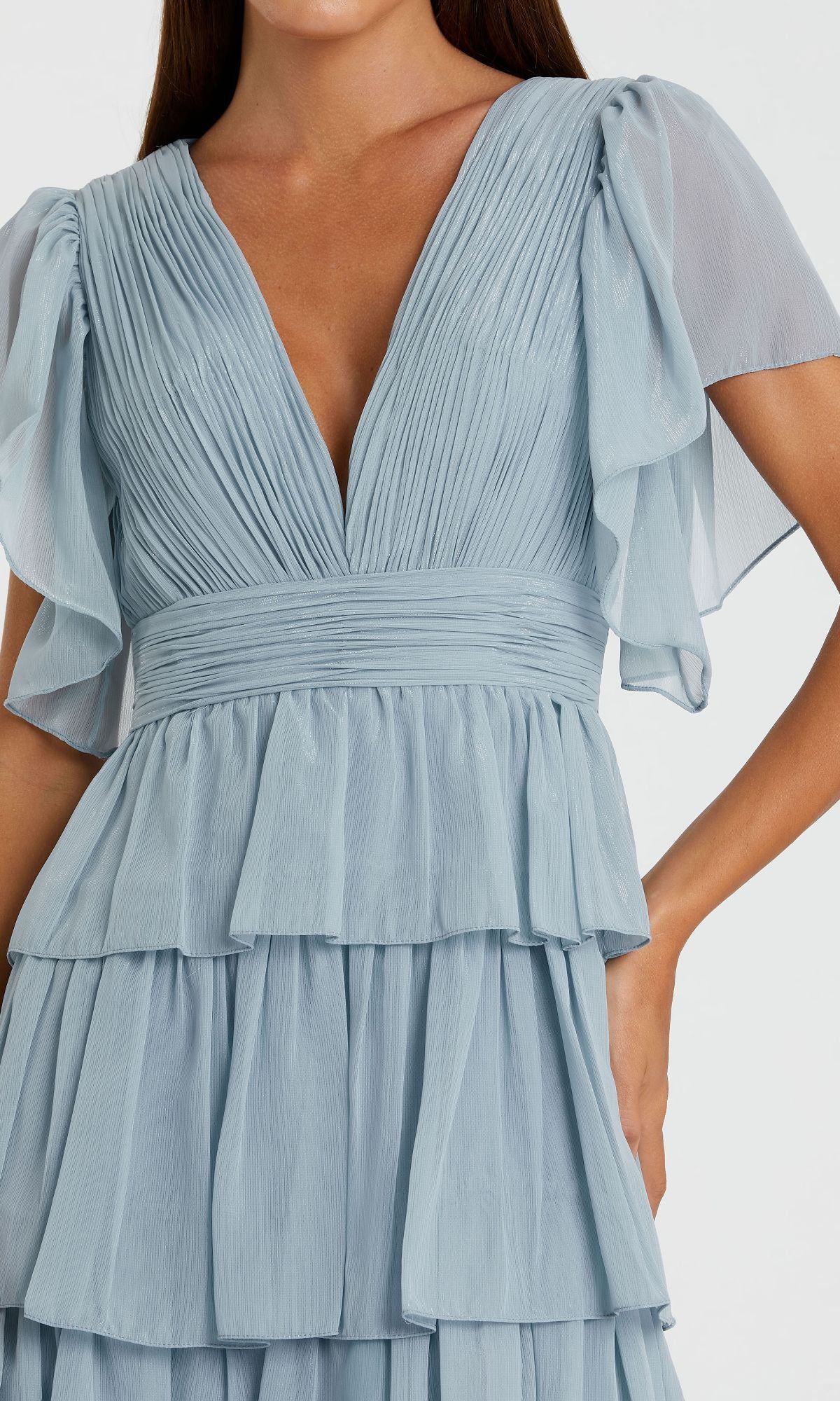 A woman models the Mac Duggal 49595 Flutter-Sleeve Long Formal Dress in light blue, featuring pleats, layered ruffles, and flutter sleeves, shown from shoulders to mid-thigh.